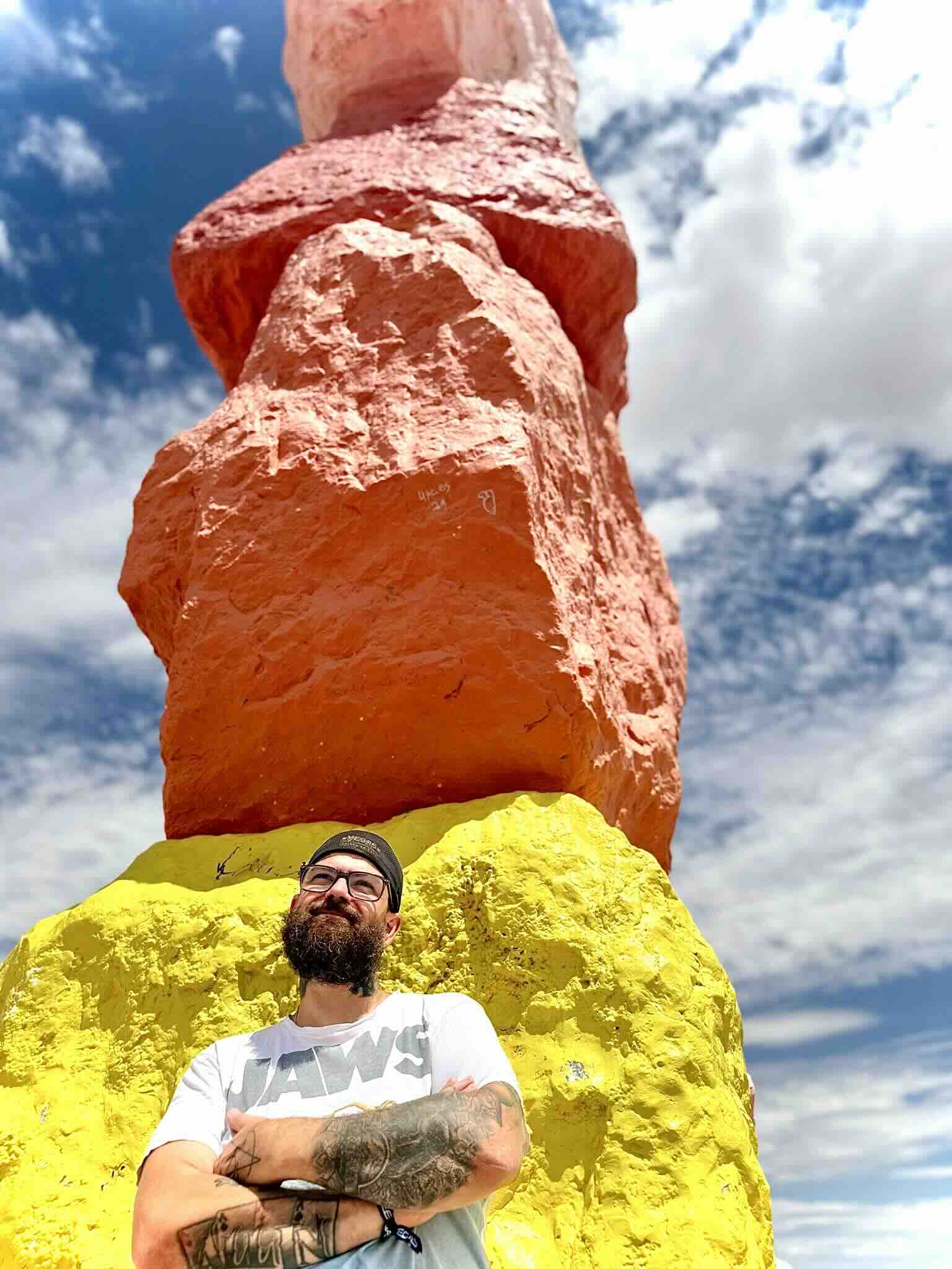 Yohan Jardin devant une colonne jaune et orange de Seven Magic Mountains à Las Vegas – œuvre d’Ugo Rondinone – USA