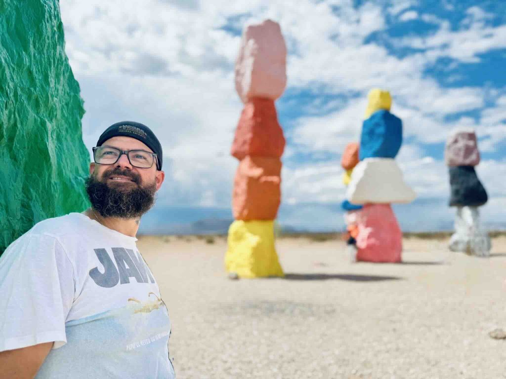 Yohan Jardin appuyé sur rocher vert à Seven Magic Mountains – Las Vegas