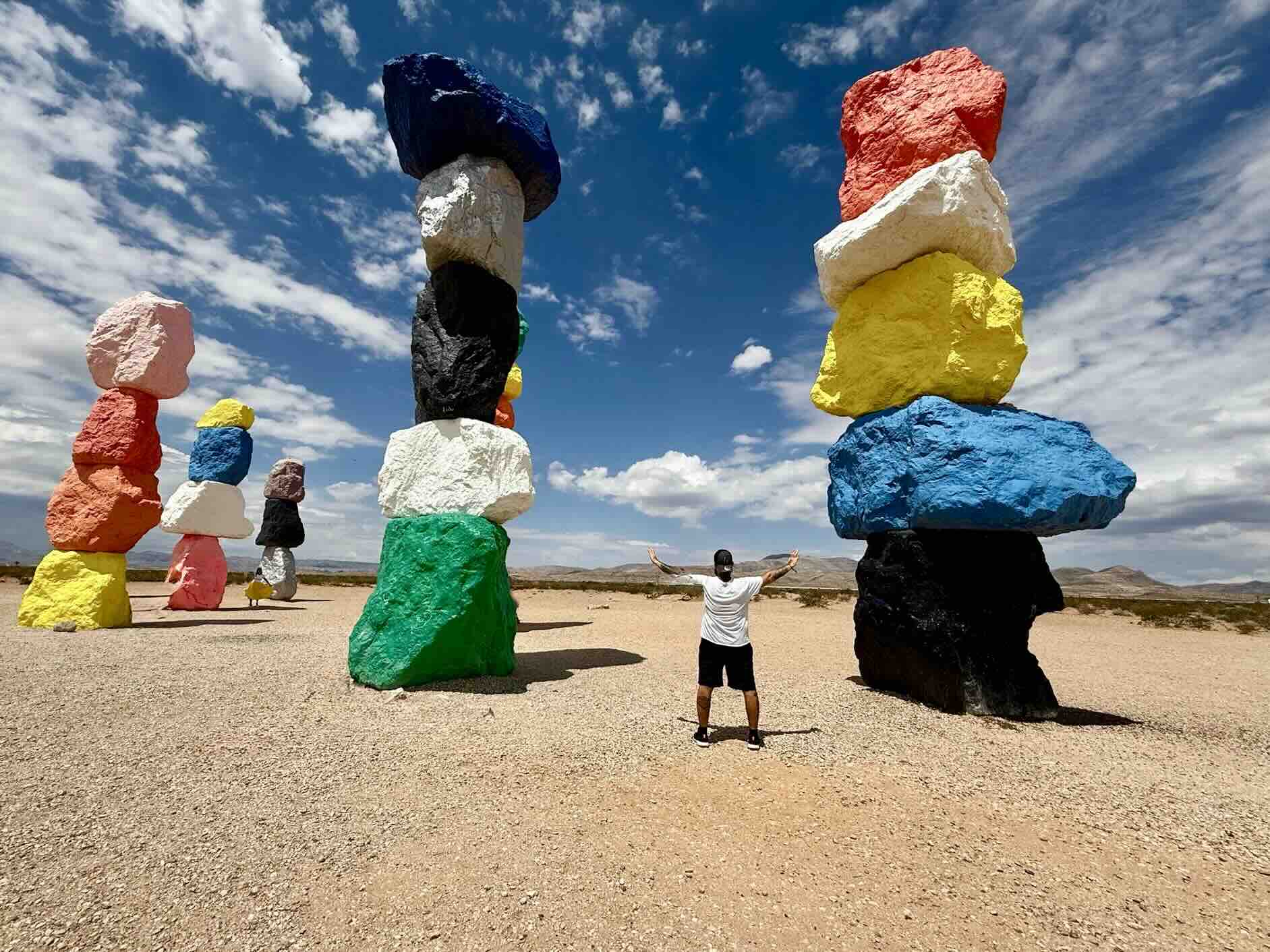 Yohan Jardin de dos, bras levés devant Seven Magic Mountains – Las Vegas