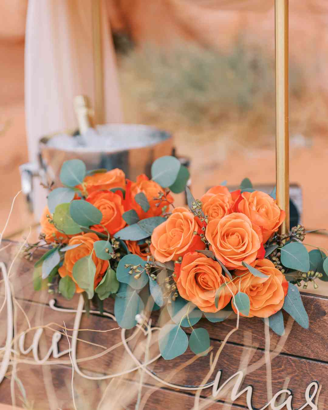 Bouquet de roses oranges et feuilles vertes avec seau à champagne