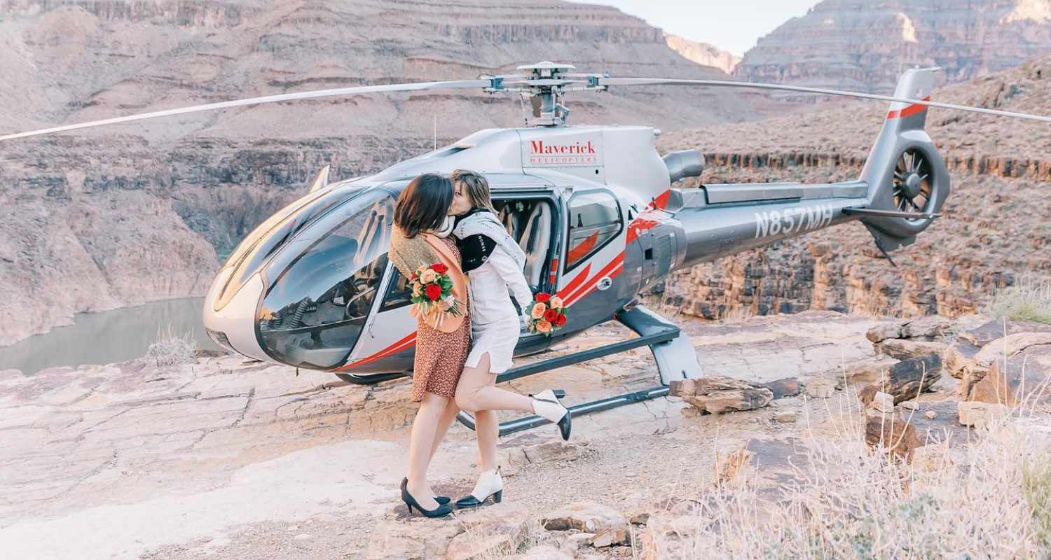 Mariées s’embrassant devant un hélicoptère au sommet d’un canyon