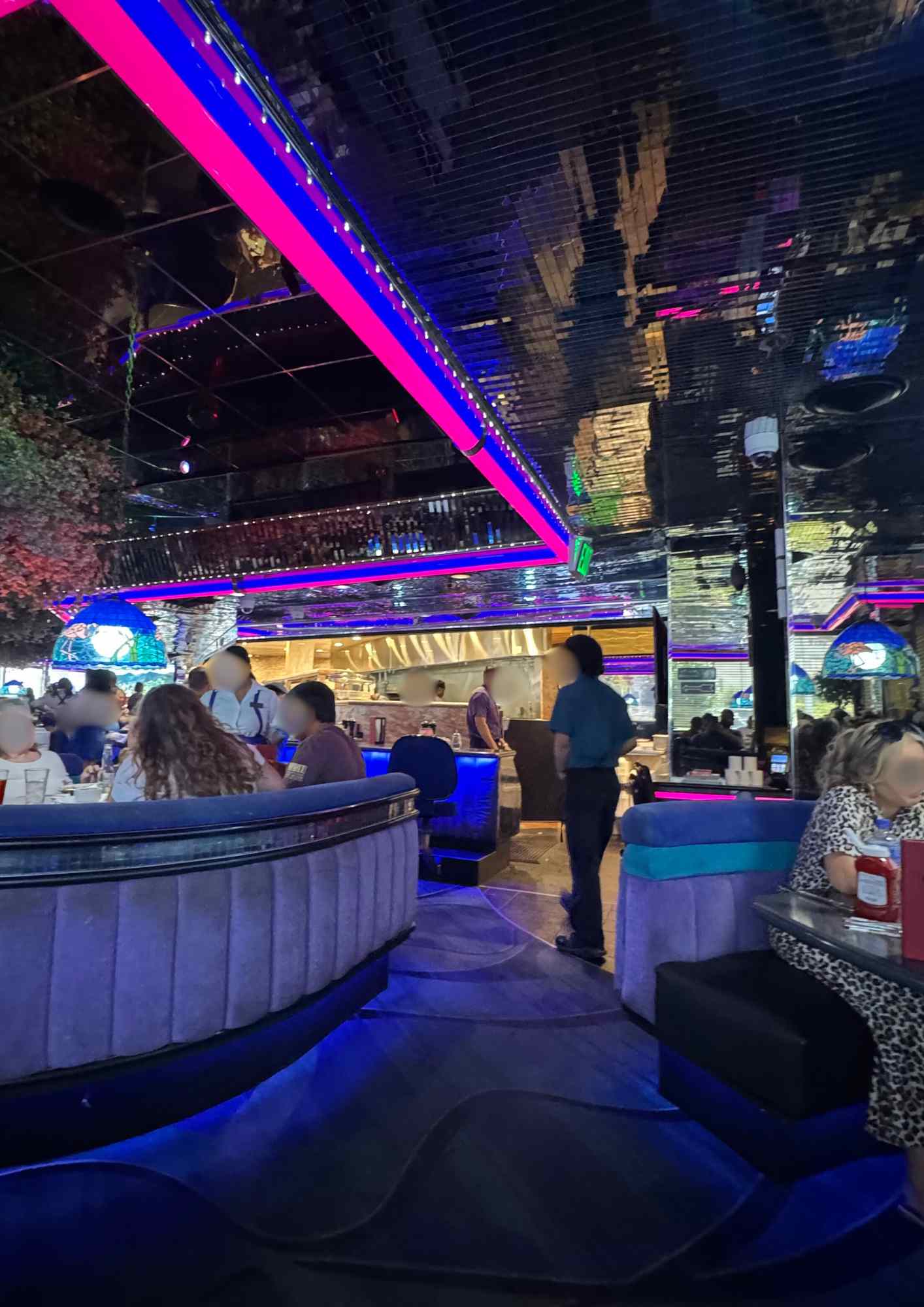 Peppermill Las Vegas – salle rétro avec banquettes violettes, néons rose/violet, plafond miroir et cuisine ouverte