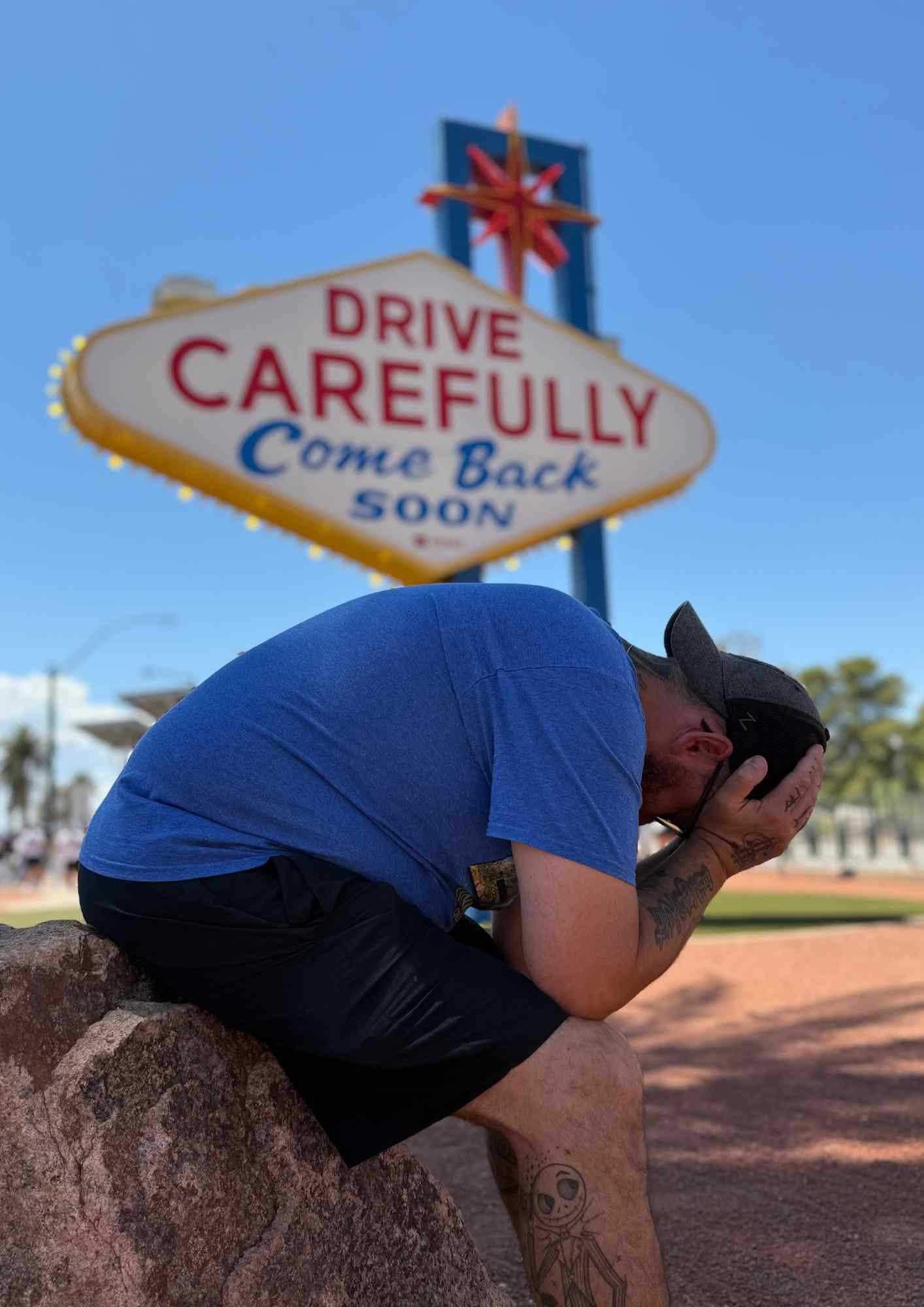 Yo assis devant le panneau “Drive Carefully – Come Back Soon” à Las Vegas