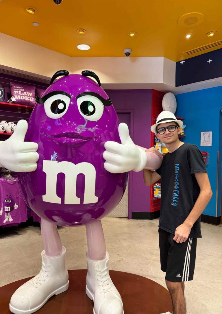 Visiteur posant avec la statue M&M’s Purple à l’intérieur