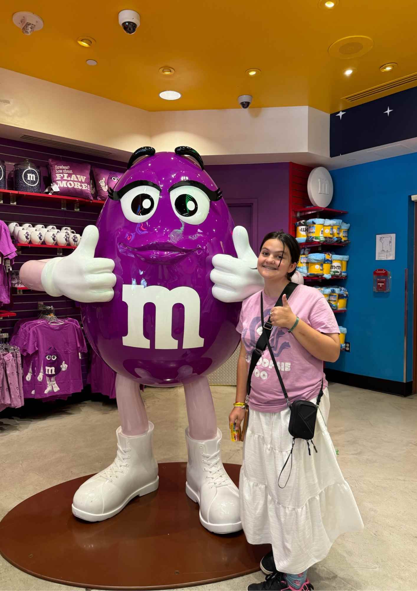 Lola souriante devant la statue M&M’s Purple