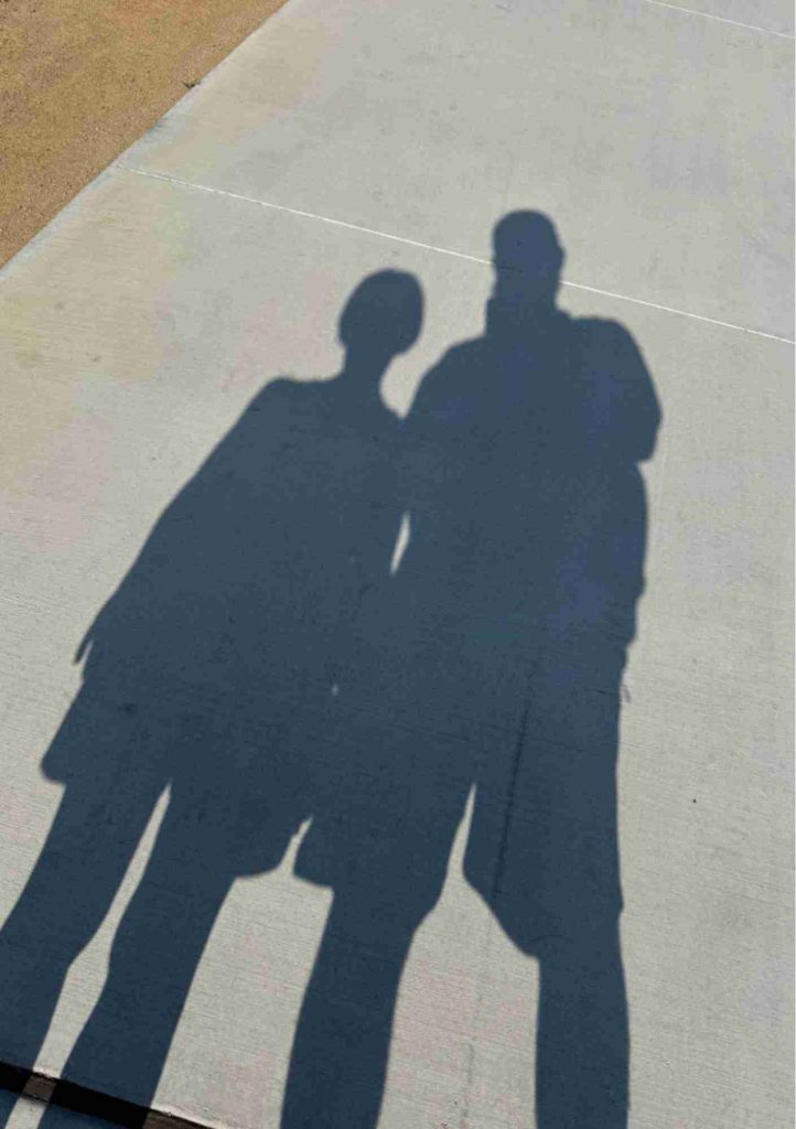 Ombres de deux personnes projetées côte à côte sur un sol clair.