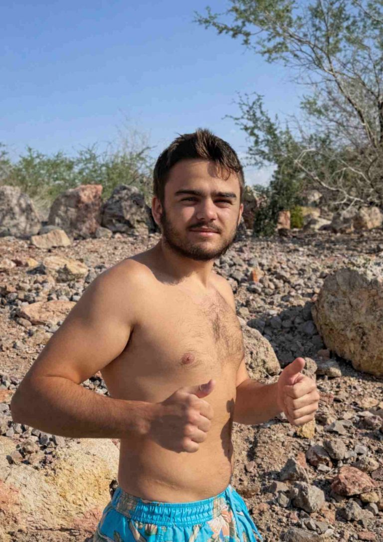 Personne torse nu faisant un signe pouce levé dans un paysage rocailleux.