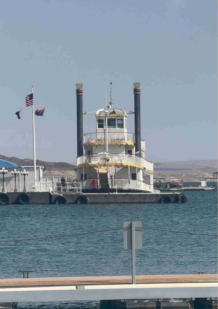 Bateau amarré sur un plan d’eau, avec une structure à plusieurs ponts et deux cheminées.