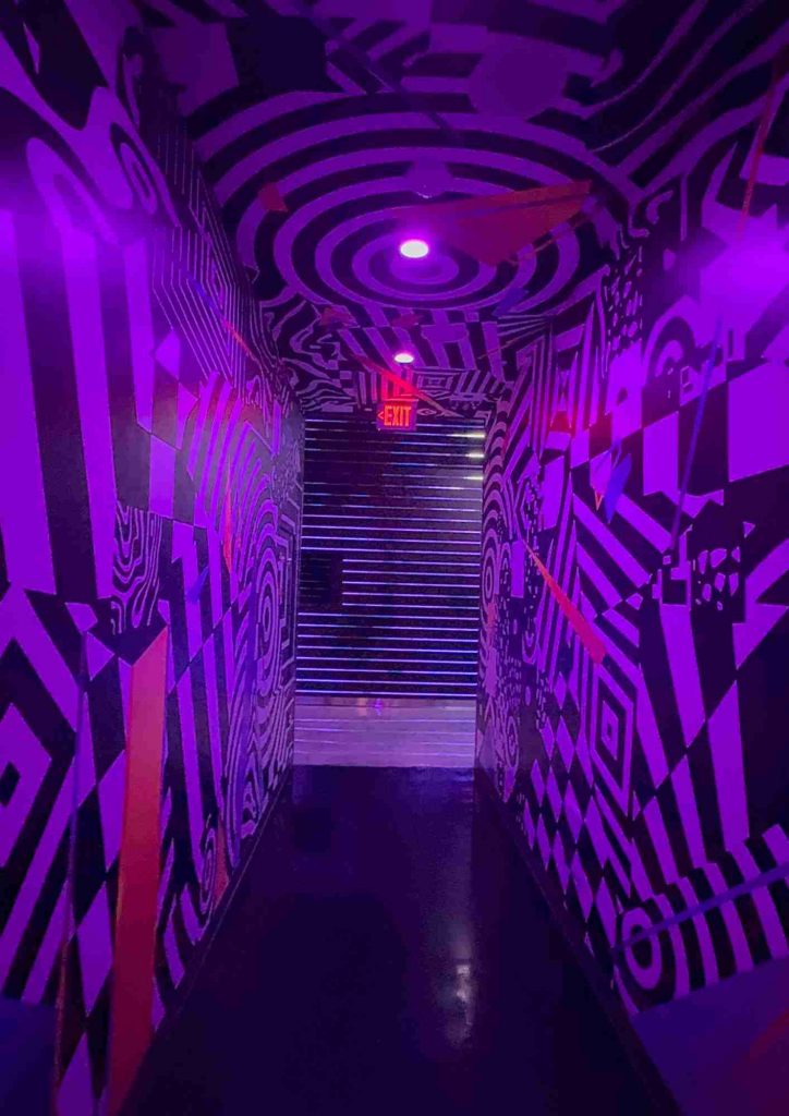 Couloir graphique noir et violet dans les espaces immersifs de Omega Mart